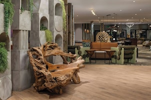 Un vestíbulo moderno con una gran escultura de madera, zona de estar y un bar.