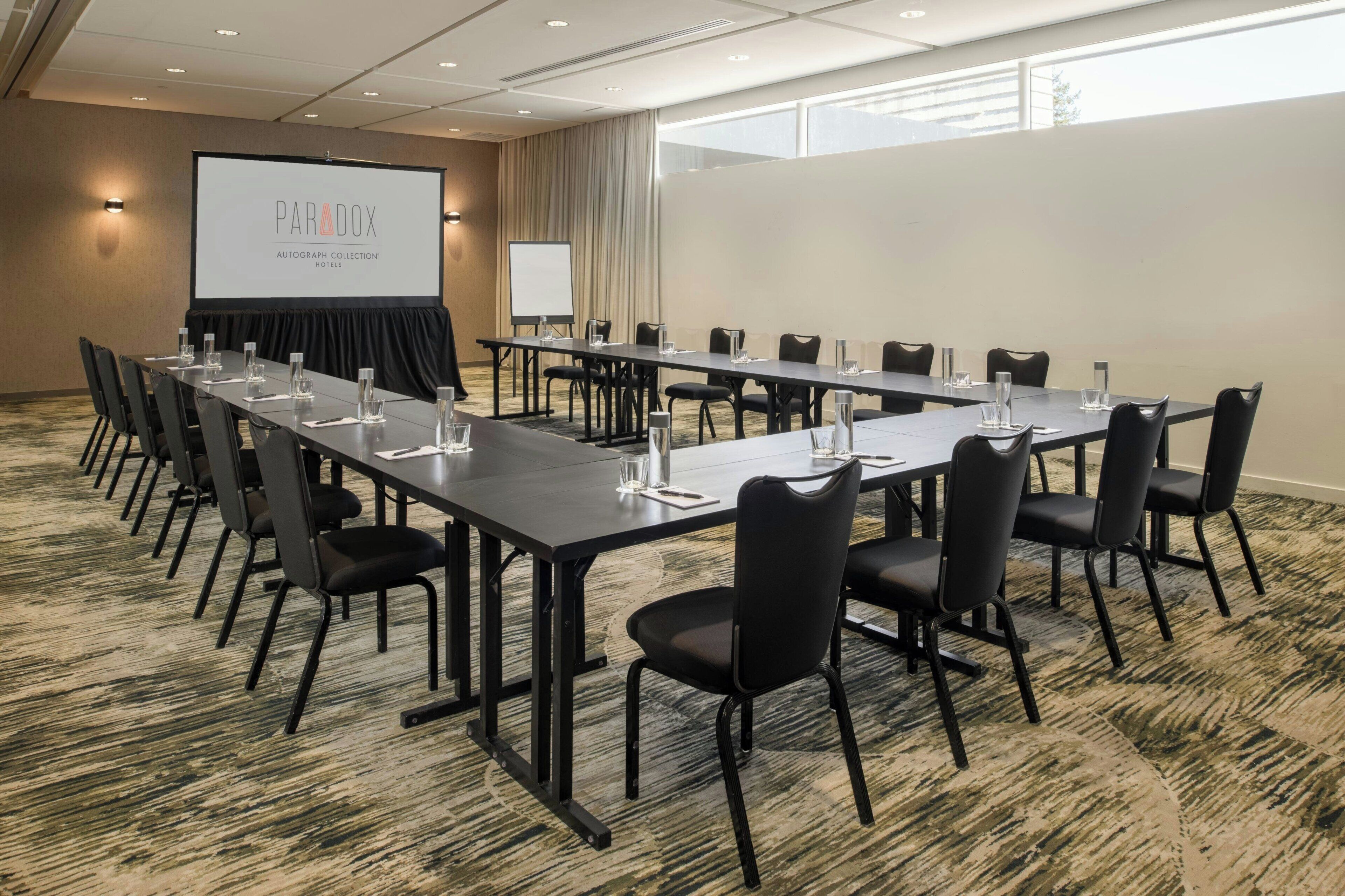 A conference room with a long table, chairs, a projector screen, and a whiteboard.