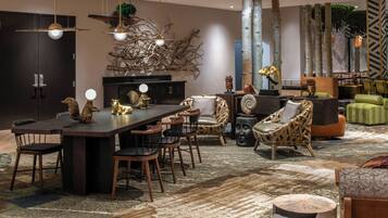 A modern living room with a dark wood dining table, comfortable seating, and a large tree sculpture.