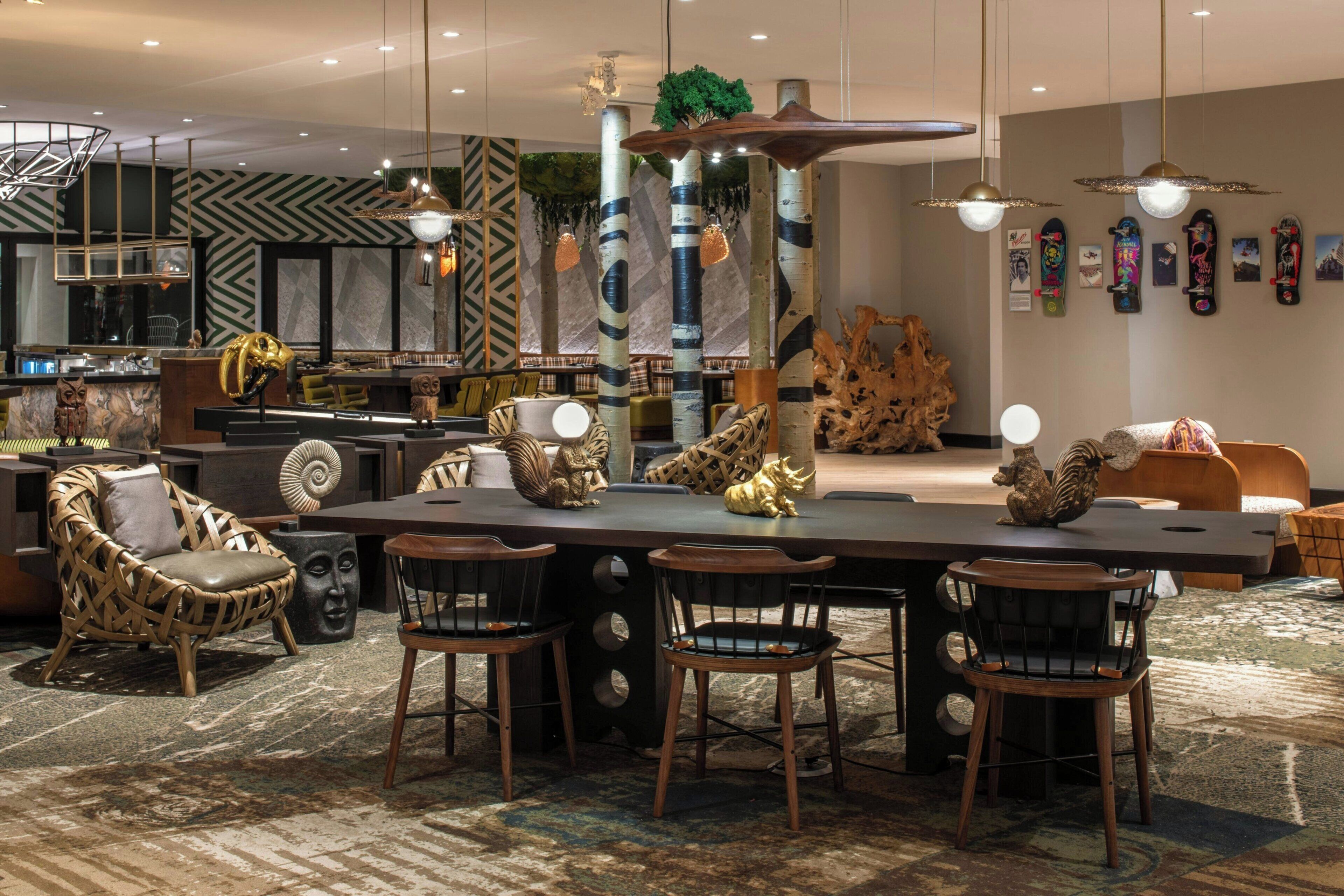 A modern dining area with a long table, chairs, and a central decorative column.