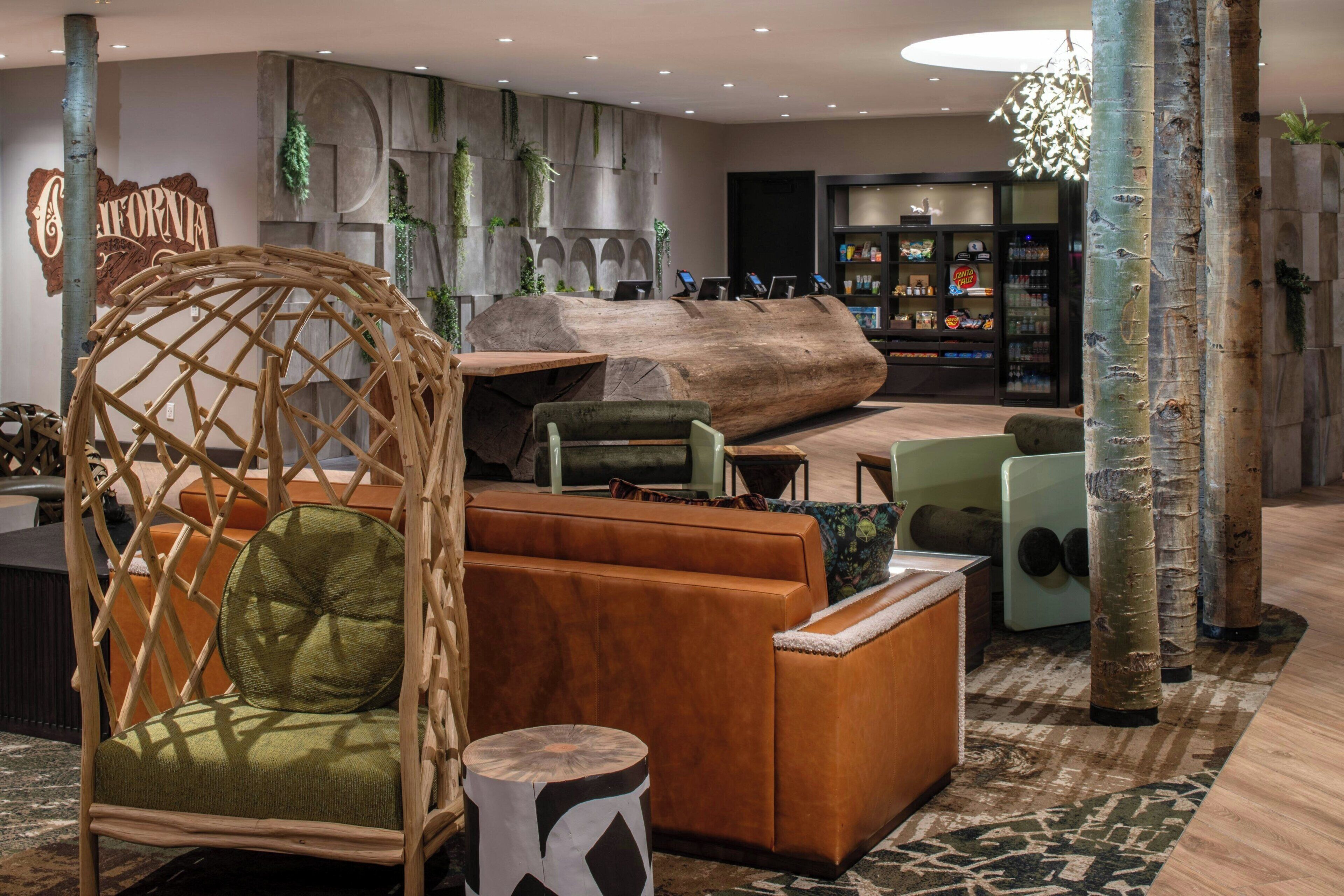 Un espace de détente moderne avec une grande table en bois massif, des sièges confortables et un mur décoratif sur lequel est inscrit le mot « Californie ».
