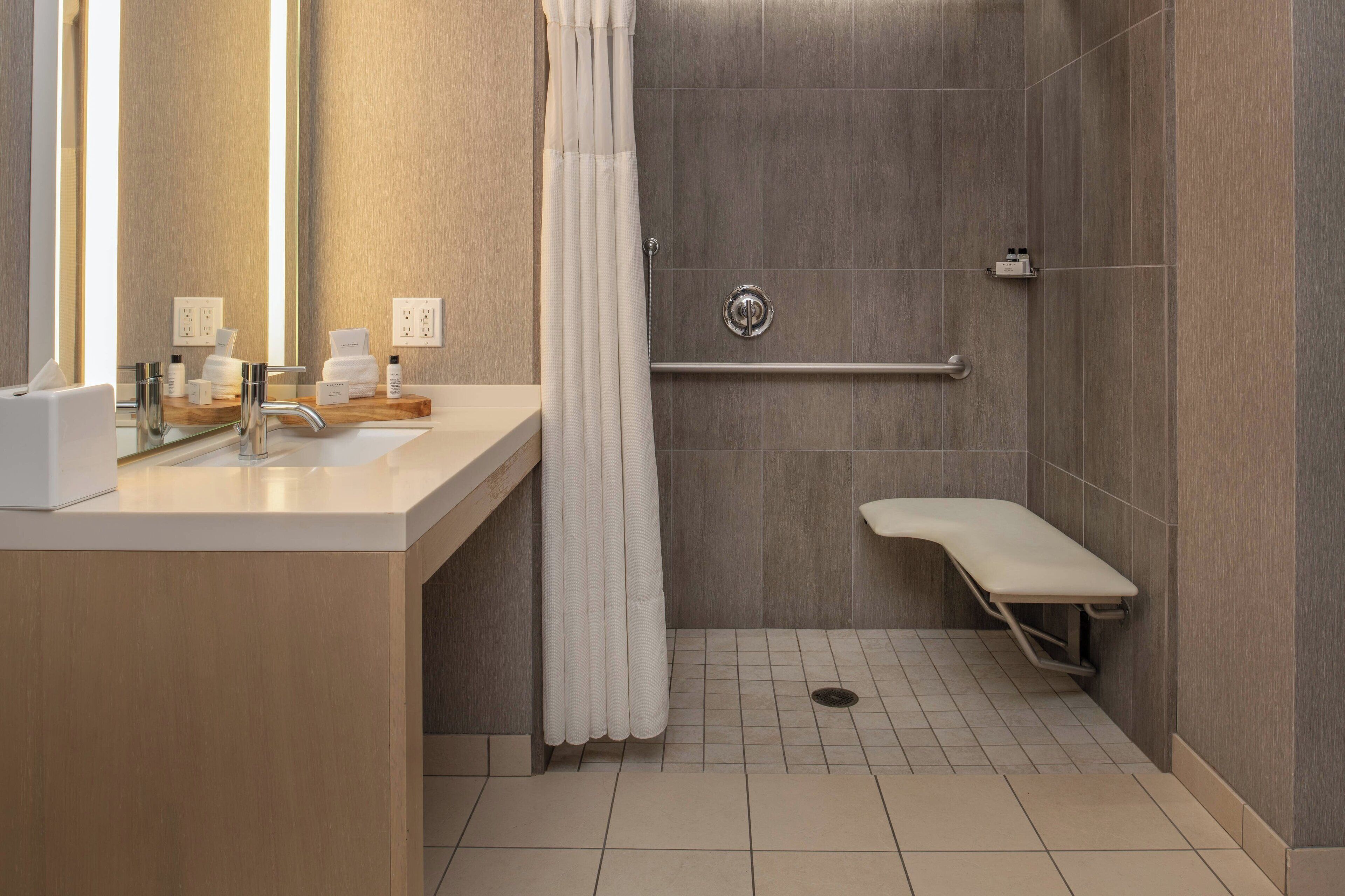 A modern bathroom with a shower, a vanity with a mirror, and a bench.