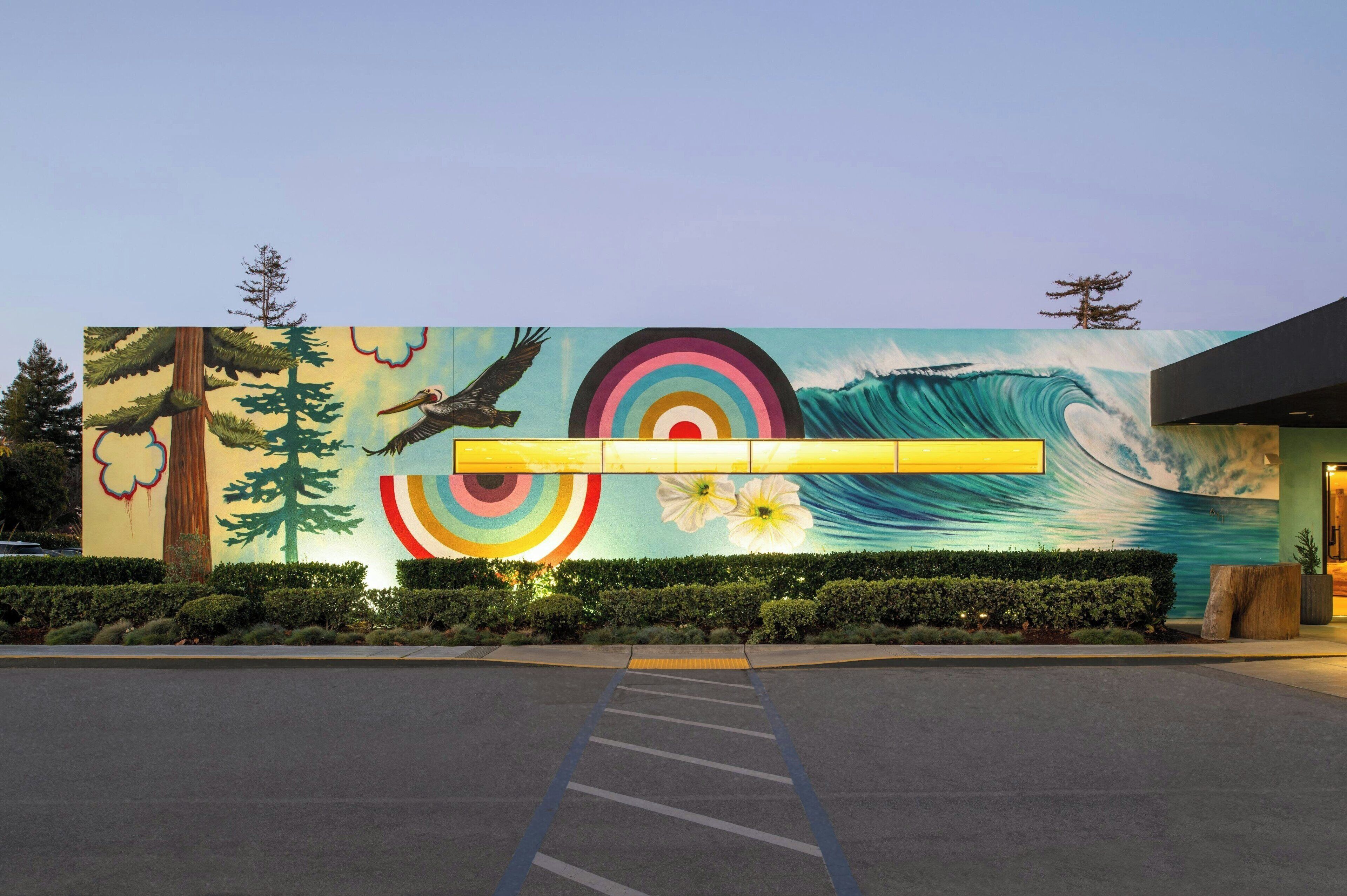 A building with a mural of a wave, trees, and a bird.