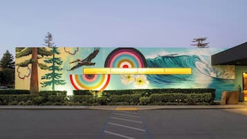 Um edifício com um mural de uma onda, árvores e um pássaro.