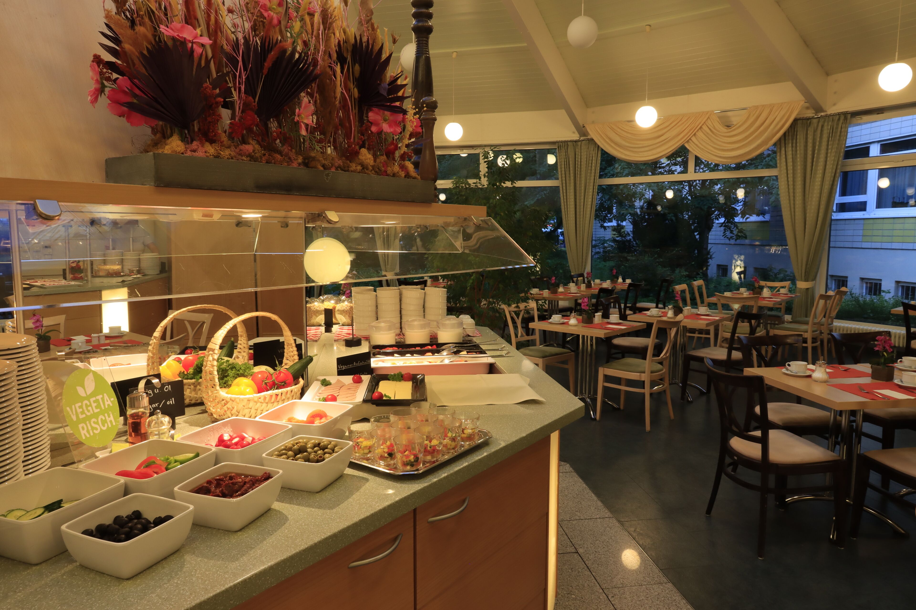 A buffet area with various food items and a seating area with tables and chairs.