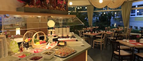 Zona de bufé con diferentes opciones de comida y un área de estar con mesas y sillas.