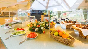 Une table de buffet garnie de divers plats et agrémentée d’une composition florale décorative.