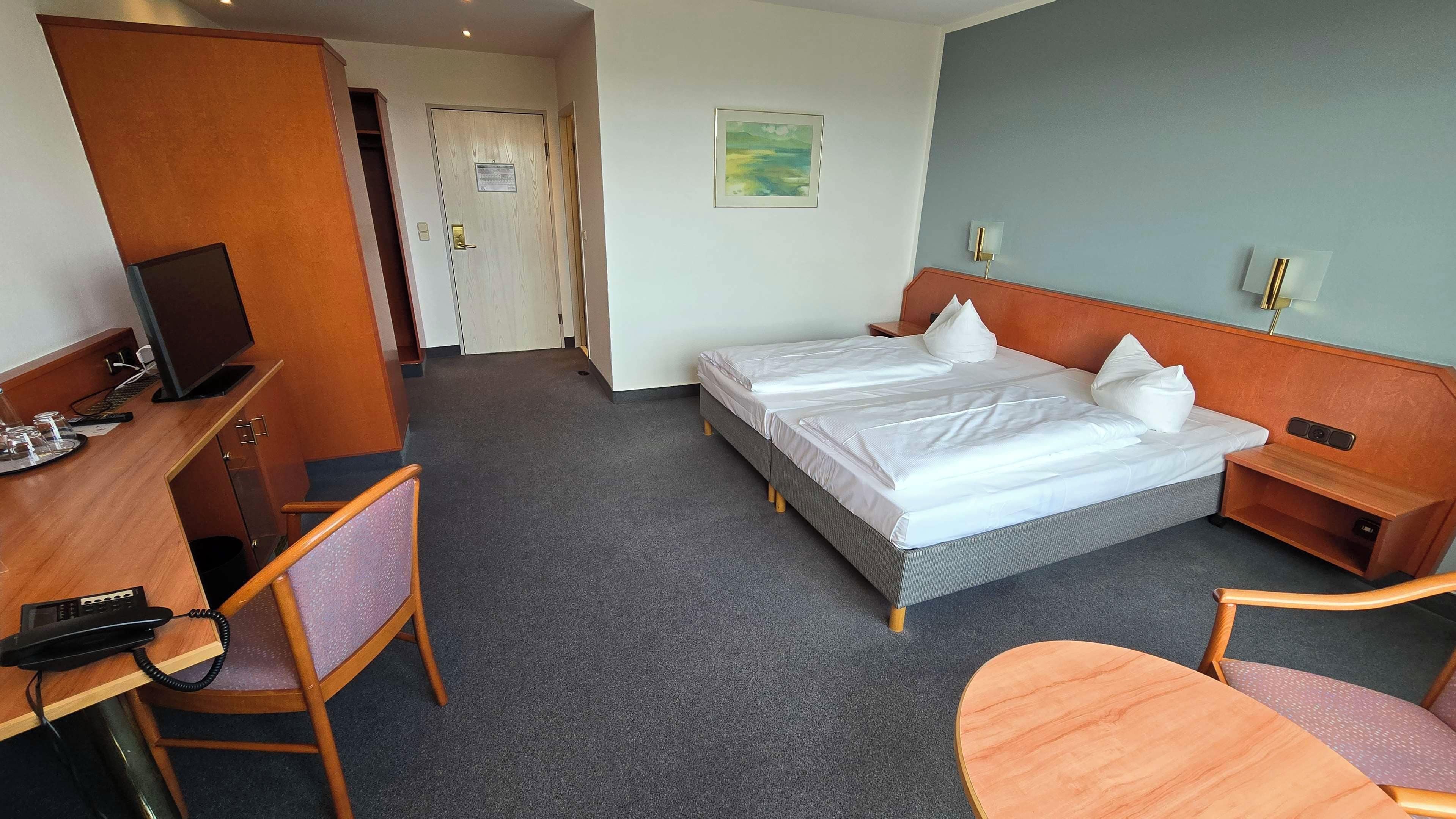 Una habitación de hotel con cama, escritorio, silla y una mesita.