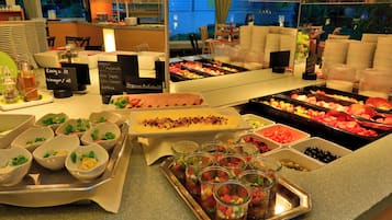 A buffet with various food options including salads, fruits, and vegan dishes.