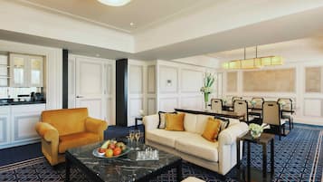 A spacious living area with a sofa, armchair, and a coffee table. There is a dining area with chairs and a chandelier.