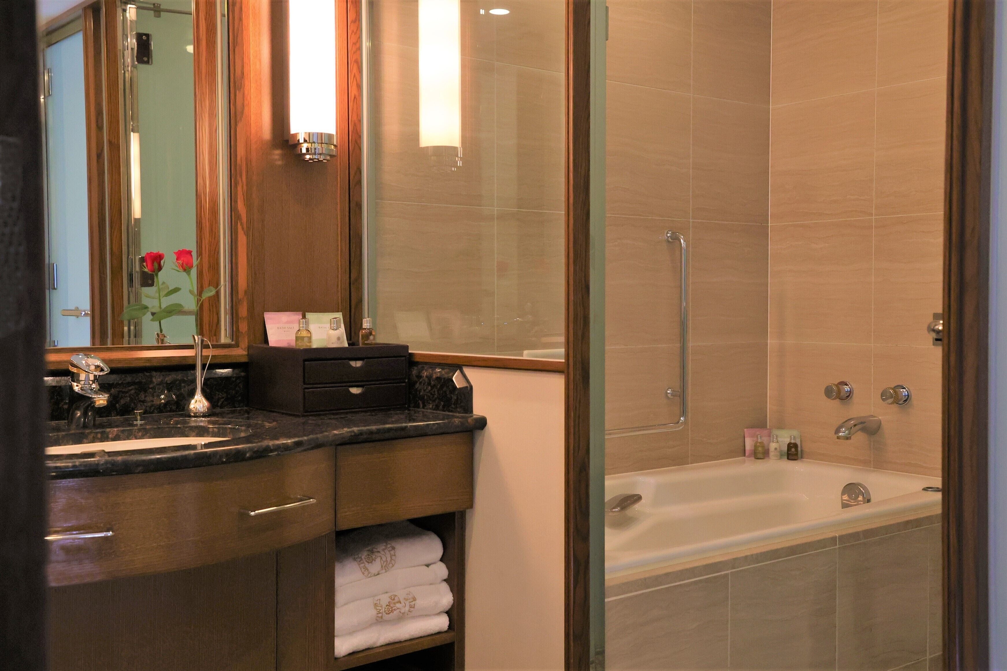 A modern bathroom with a glass-enclosed shower, a large bathtub, and a vanity with a marble countertop.