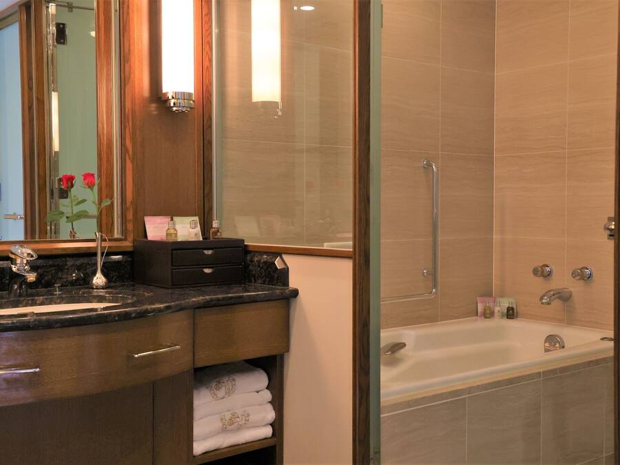 A modern bathroom with a glass-enclosed shower, a large bathtub, and a vanity with a marble countertop.