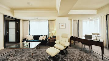 A hotel room with a sofa, armchair, and desk.