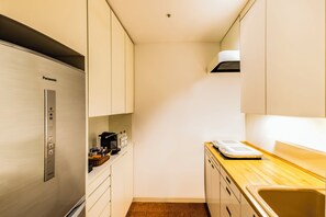 A compact kitchen with a stainless steel refrigerator, a wooden countertop, and a sink.