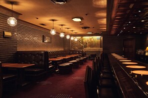 Un interior de restaurante con paredes de ladrillo, asientos de cuero y una zona de bar.