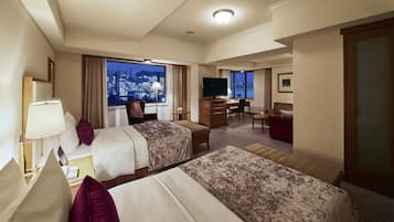 A hotel room with two beds, a desk, a TV, and a city view.