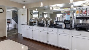 A modern kitchen with white cabinets, stainless steel appliances, and pendant lighting.