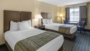 Ett hotellrum med två sängar, ett skrivbord och en stol.