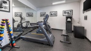 A gym with treadmills, a mirrored wall, and a wall-mounted TV.