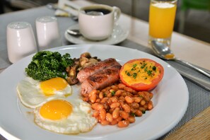 A breakfast plate with eggs, sausages, beans, and a tomato. - Capetonian Hotel (Cape Town)