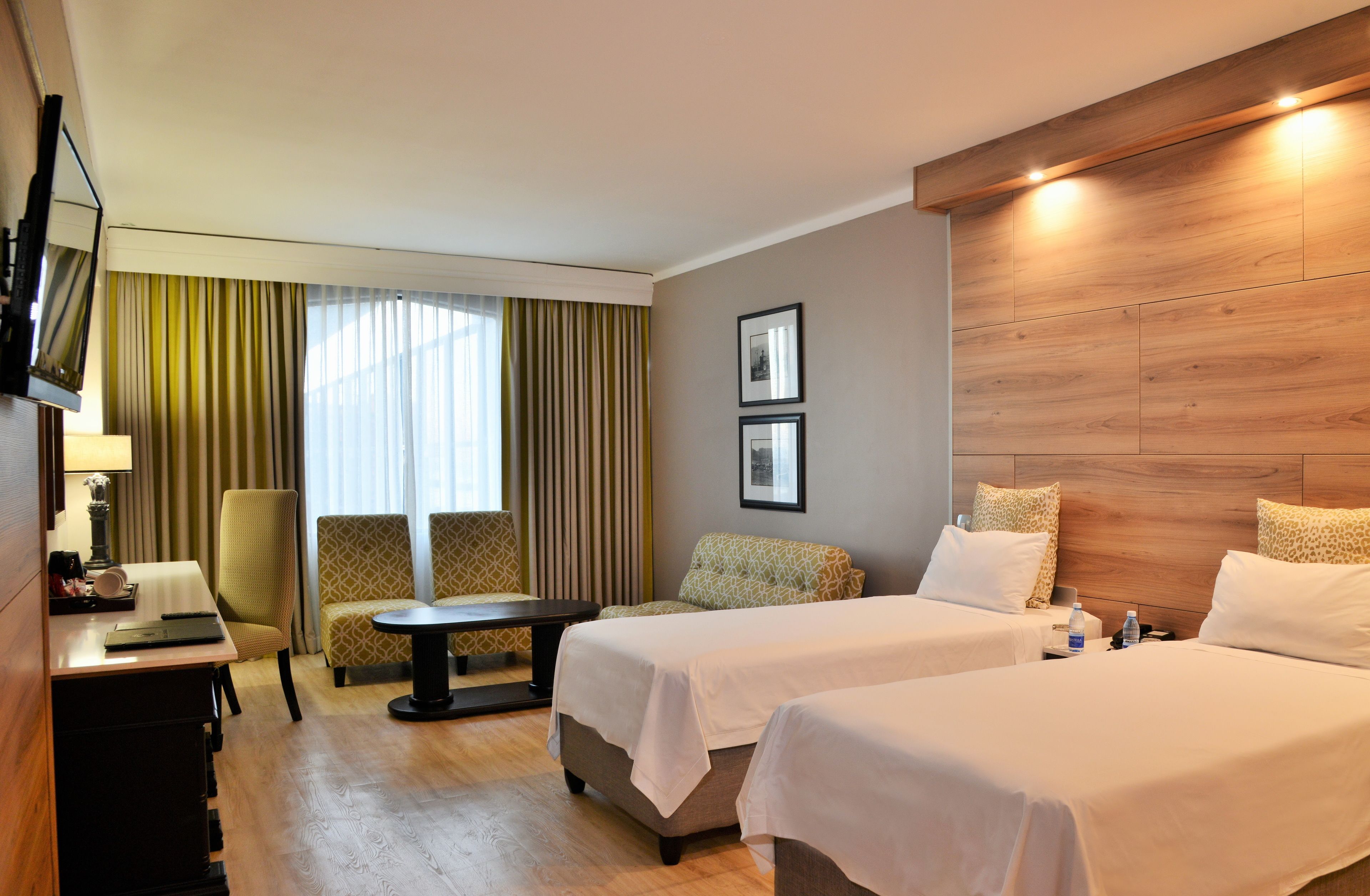 Ein Hotelzimmer mit zwei Betten, einem Schreibtisch, einem Stuhl, einem Tisch und einem Fernseher.