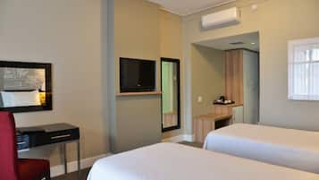 A hotel room with two beds, a desk, a chair, a TV, and a wardrobe.