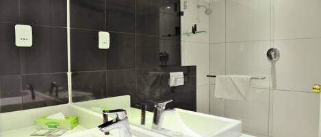 A modern bathroom with two sinks, a large mirror, and a shower area.
