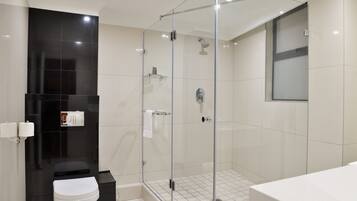 A modern bathroom with a glass-enclosed shower, a white toilet, and a large bathtub.