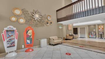 A hotel lobby with a reception desk, seating area, and decorative wall art.