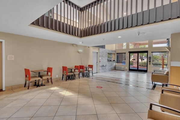 A spacious indoor area with a high ceiling, a staircase, and multiple seating arrangements.