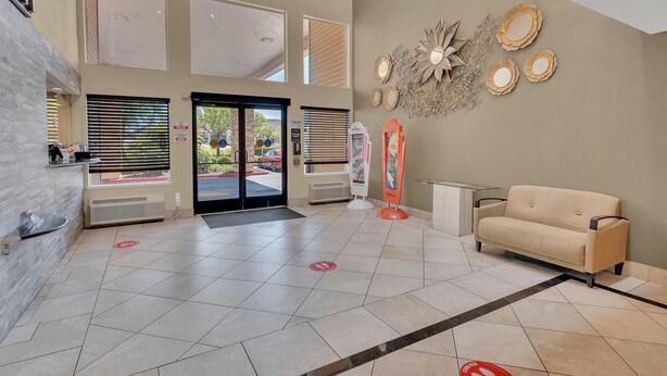 A spacious lobby with a beige sofa, large windows, and decorative wall art.