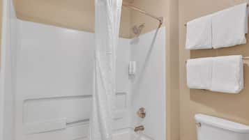 Ein Badezimmer mit Badewanne, Dusche und Toilette. Zwei weiße Handtücher hängen an der Wand.