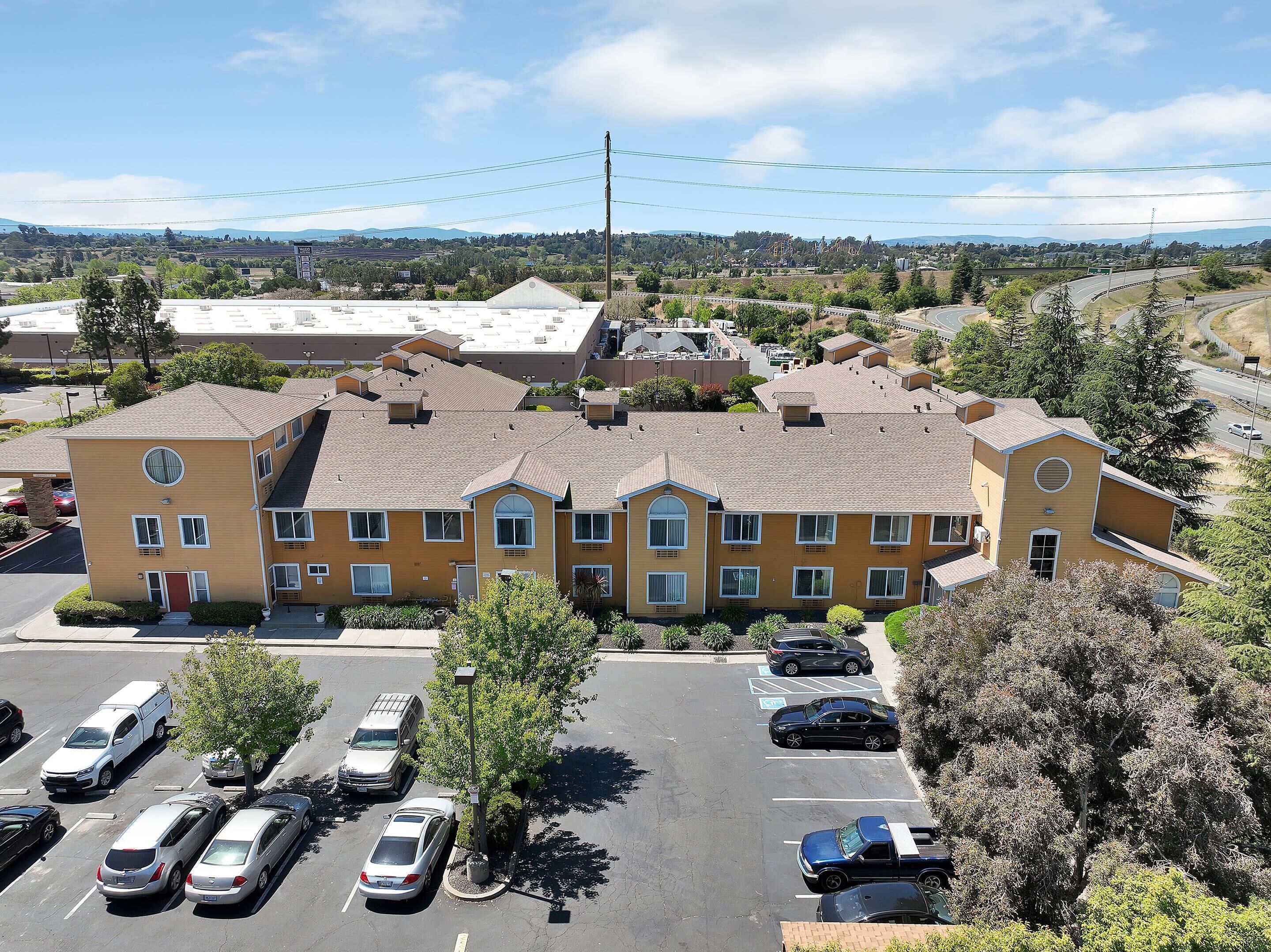 A multi-story hotel with a parking lot in front.
