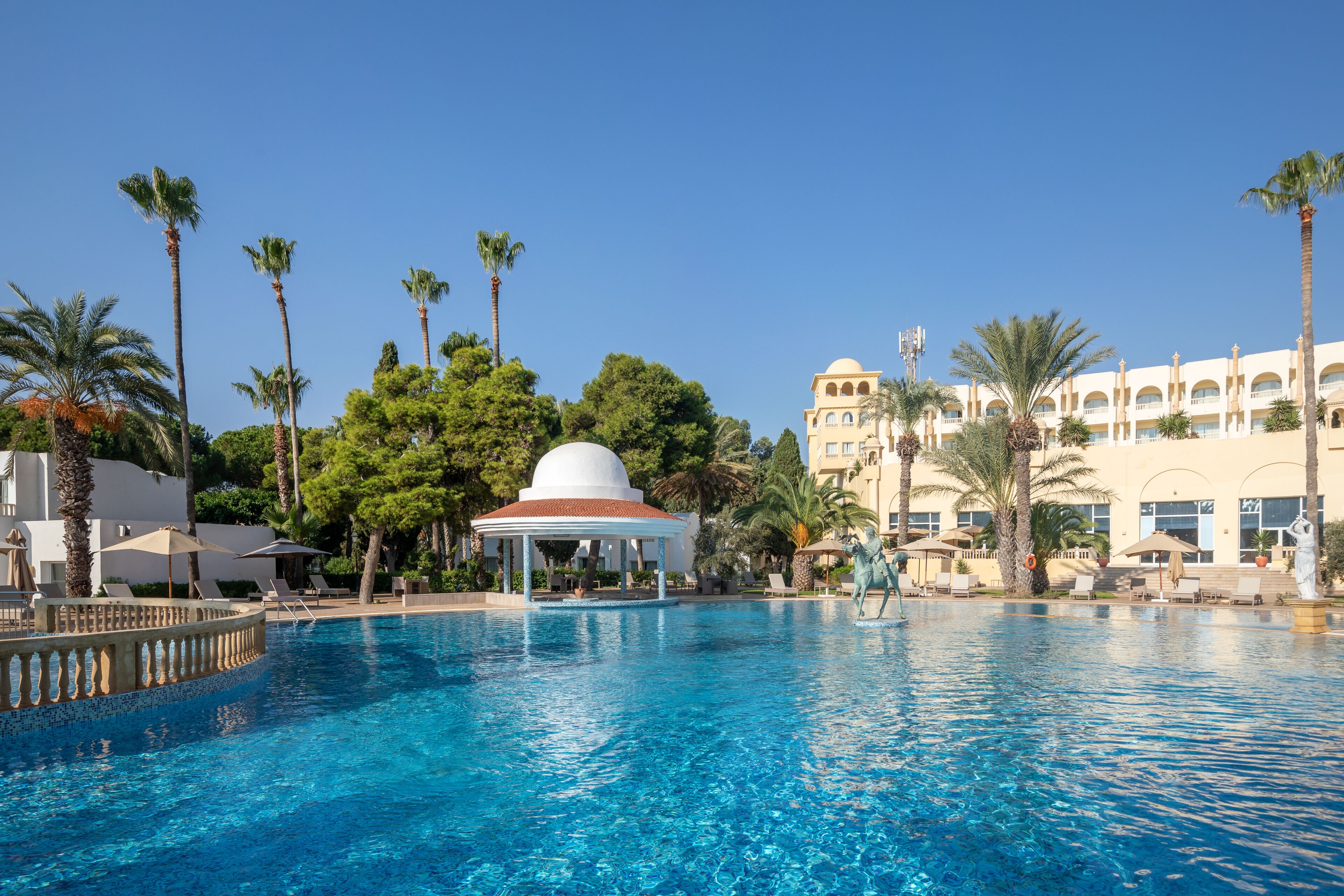 Una piscina techada, una piscina al aire libre, sombrillas