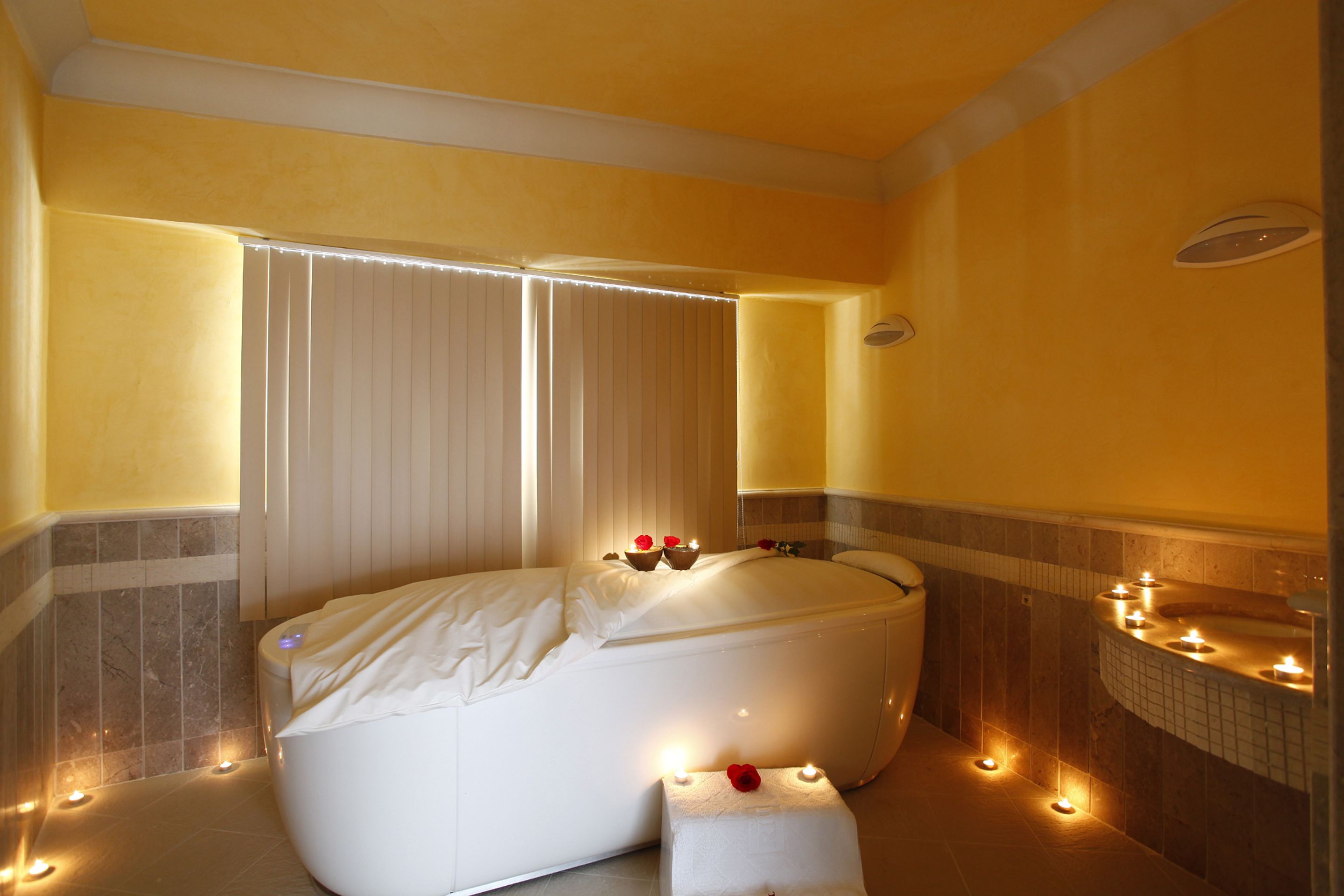 Ein modernes Badezimmer mit einer großen Badewanne, einem kleinen Hocker und Kerzen.