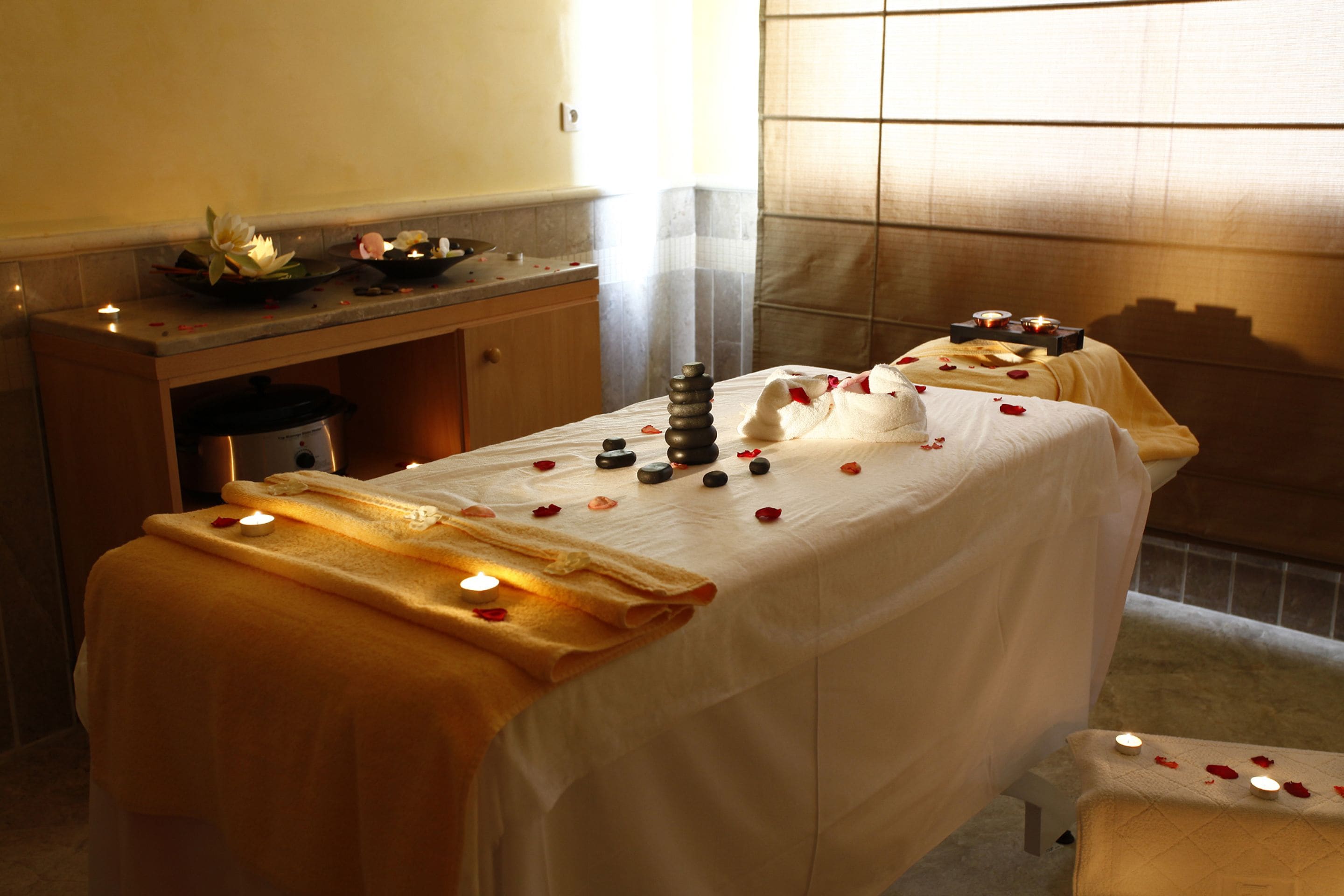 A spa treatment area with a massage table, candles, and rose petals.