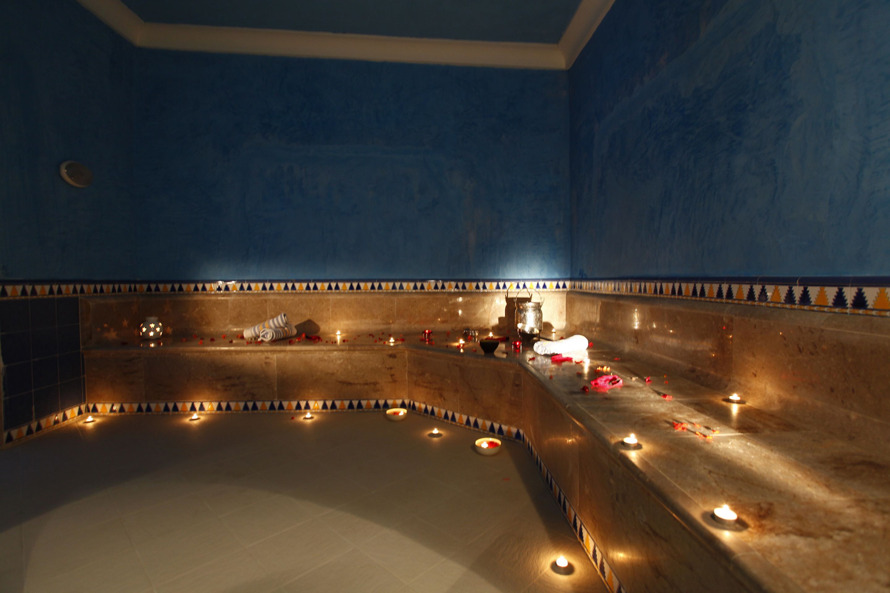 A dimly lit room with a curved bench, candles, and a patterned wall.