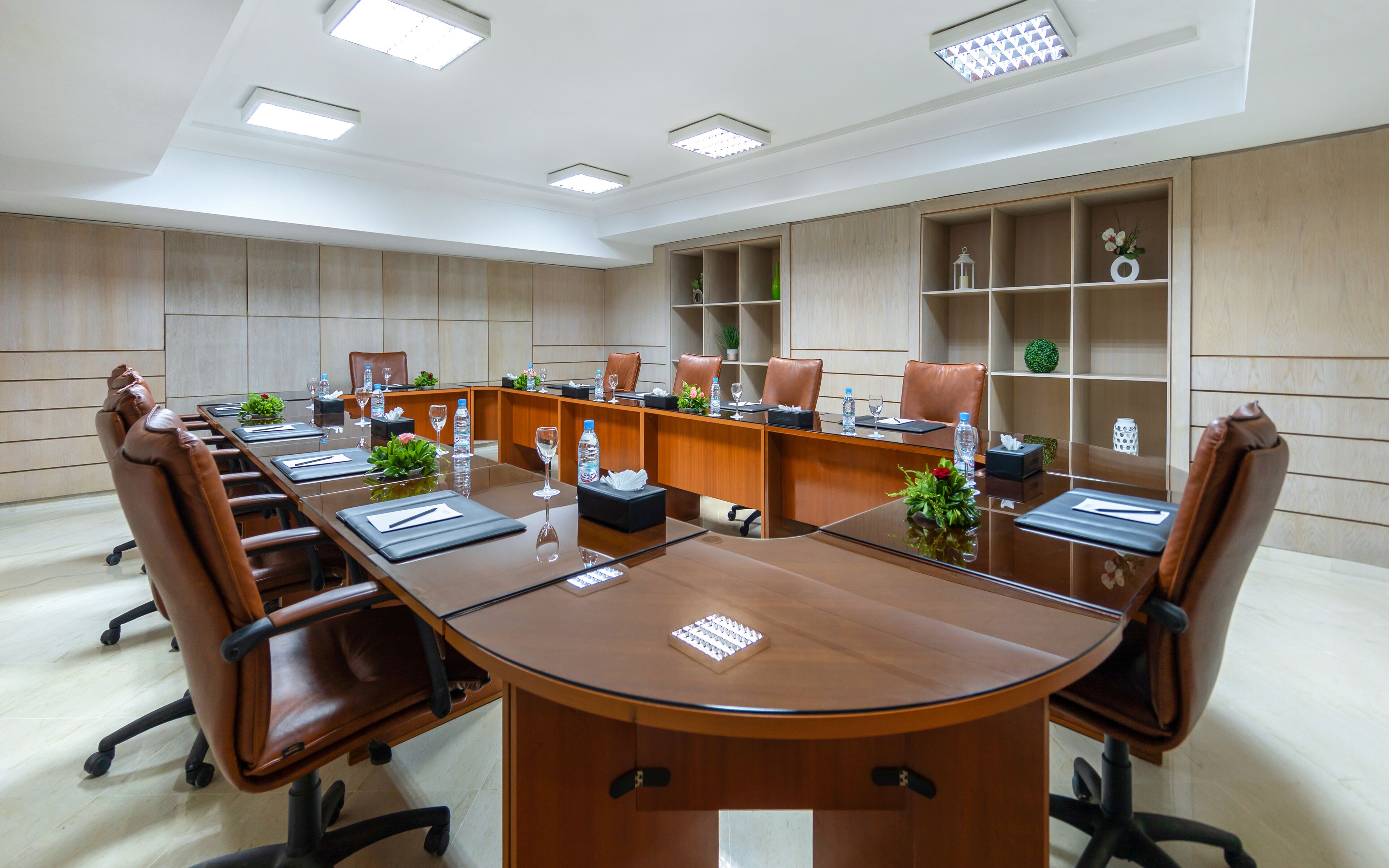 A conference room with a long table, leather chairs, and built-in shelving with decorative items.