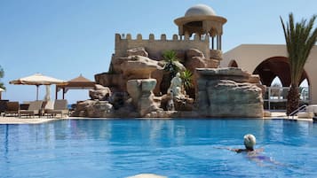 Una piscina techada, una piscina al aire libre, sombrillas