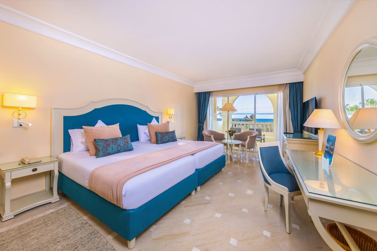 Habitació d'hotel amb un llit gran, una taula de treball i vista a l'oceà.