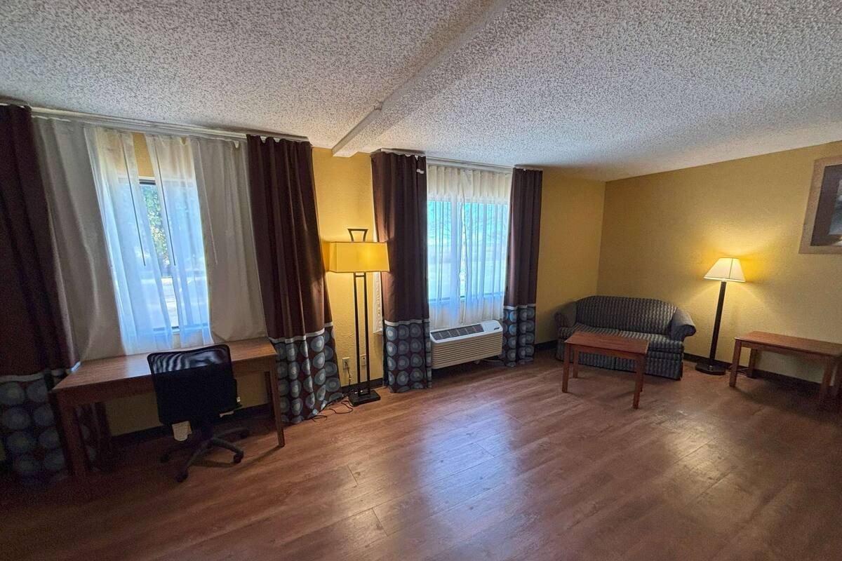 A living room with a sofa, a desk, a lamp, and a radiator.