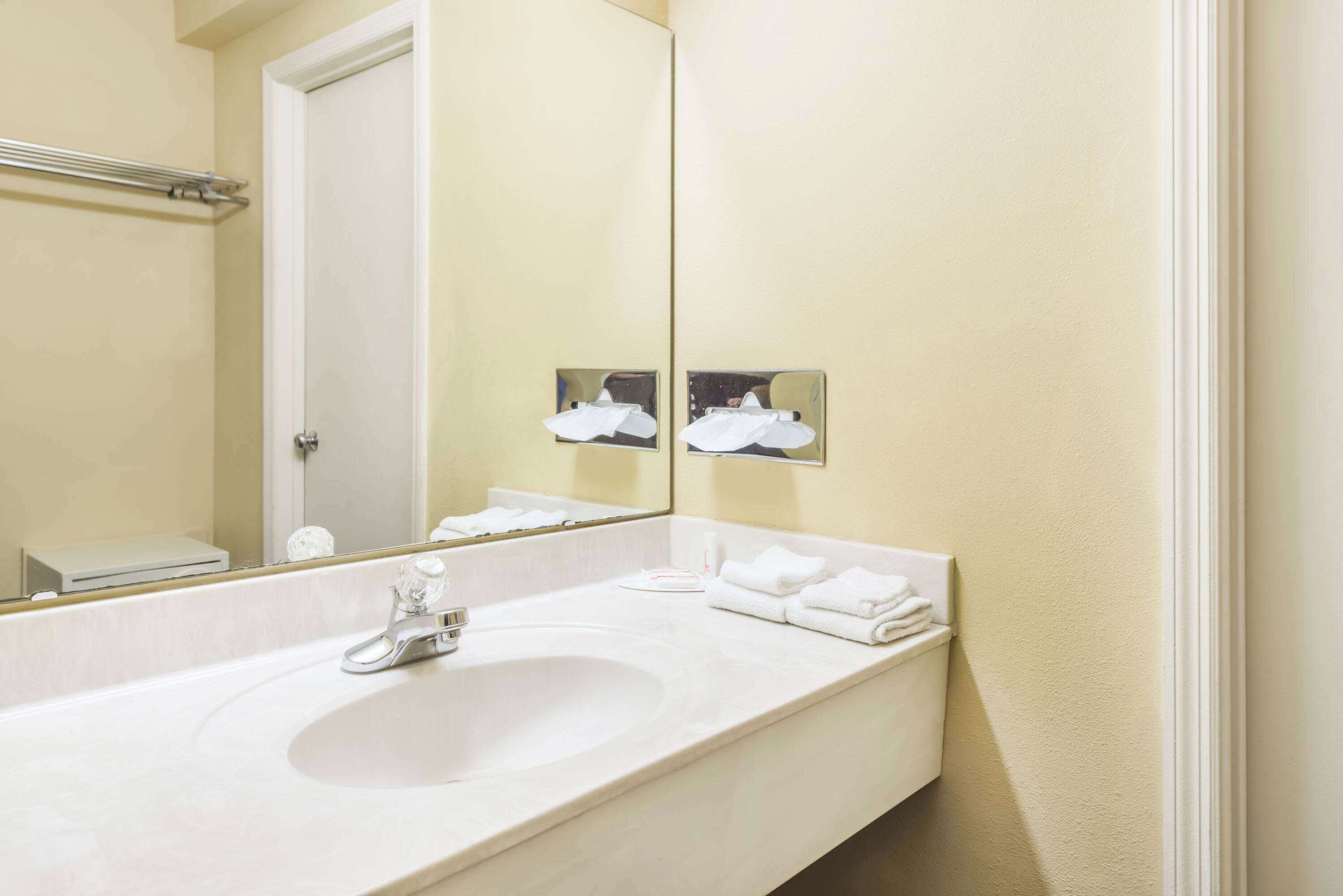 A bathroom with a white sink, a mirror, and a towel rack.