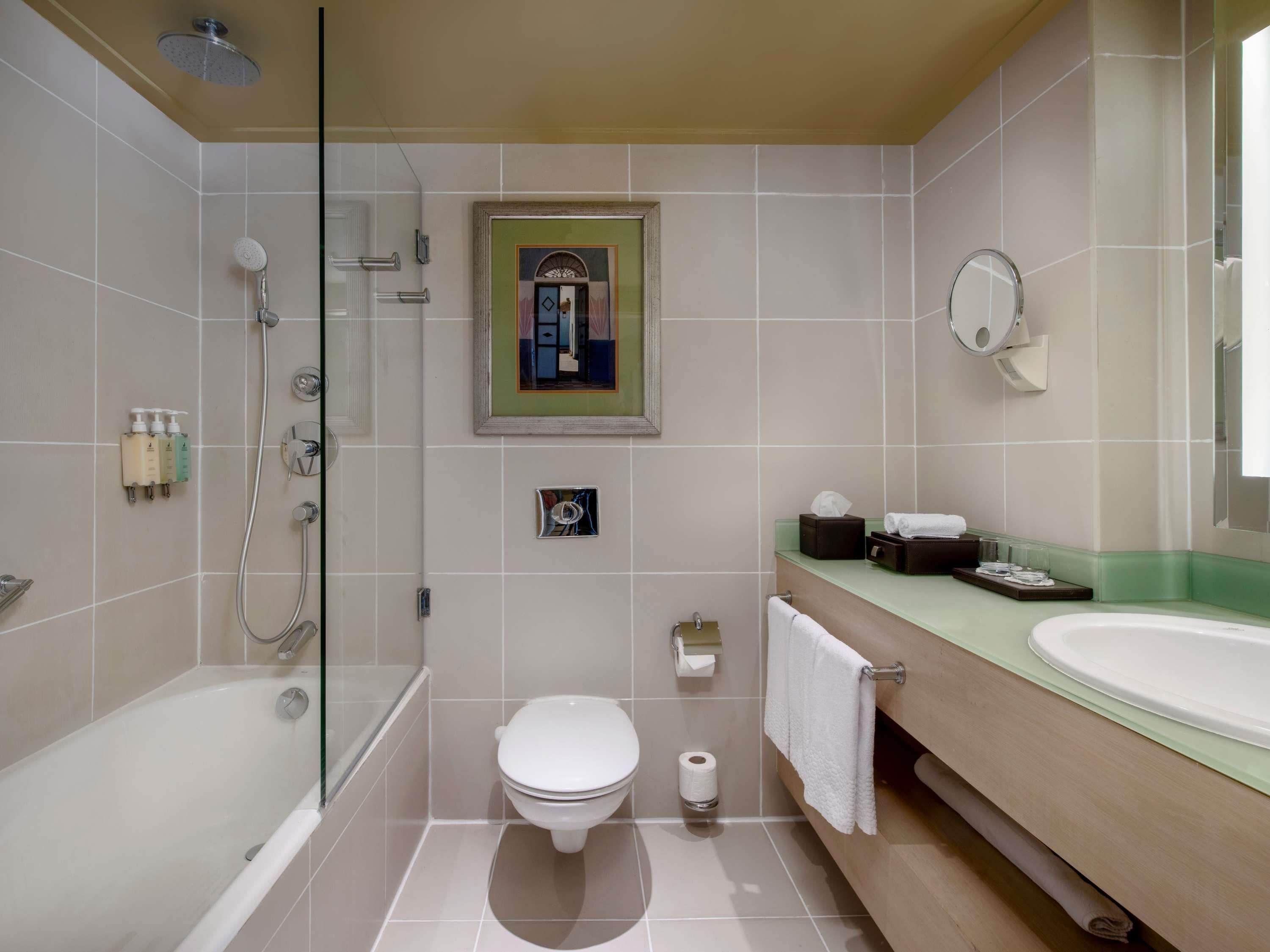 A modern bathroom with a glass-enclosed shower, a toilet, a sink, and a mirror.