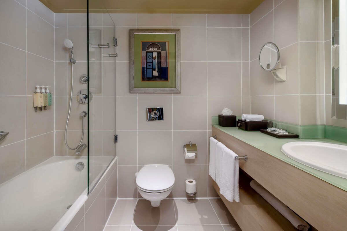 A modern bathroom with a glass-enclosed shower, a toilet, a sink, and a mirror.