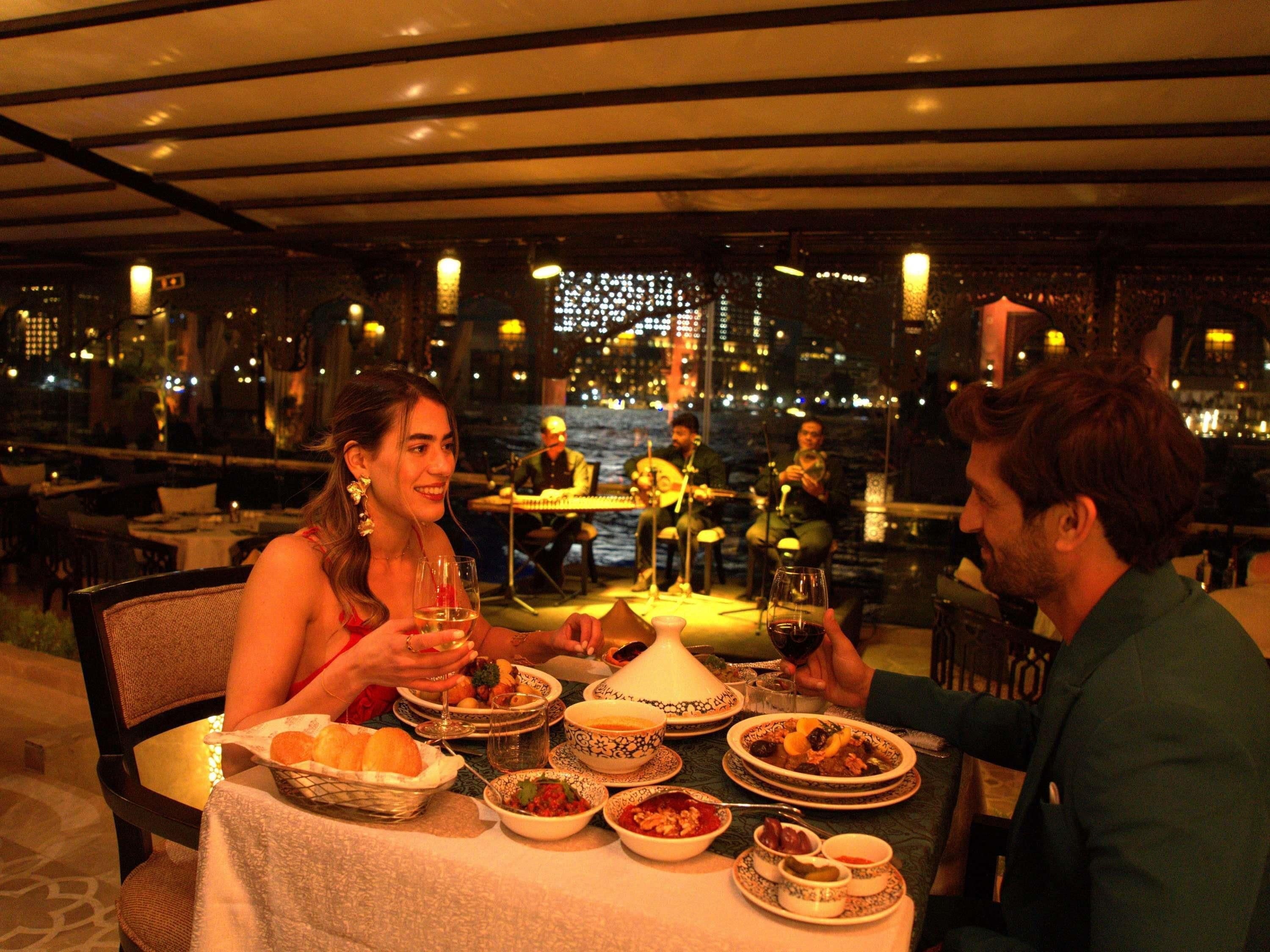 A dining table with various dishes, a city view, and a band playing in the background.