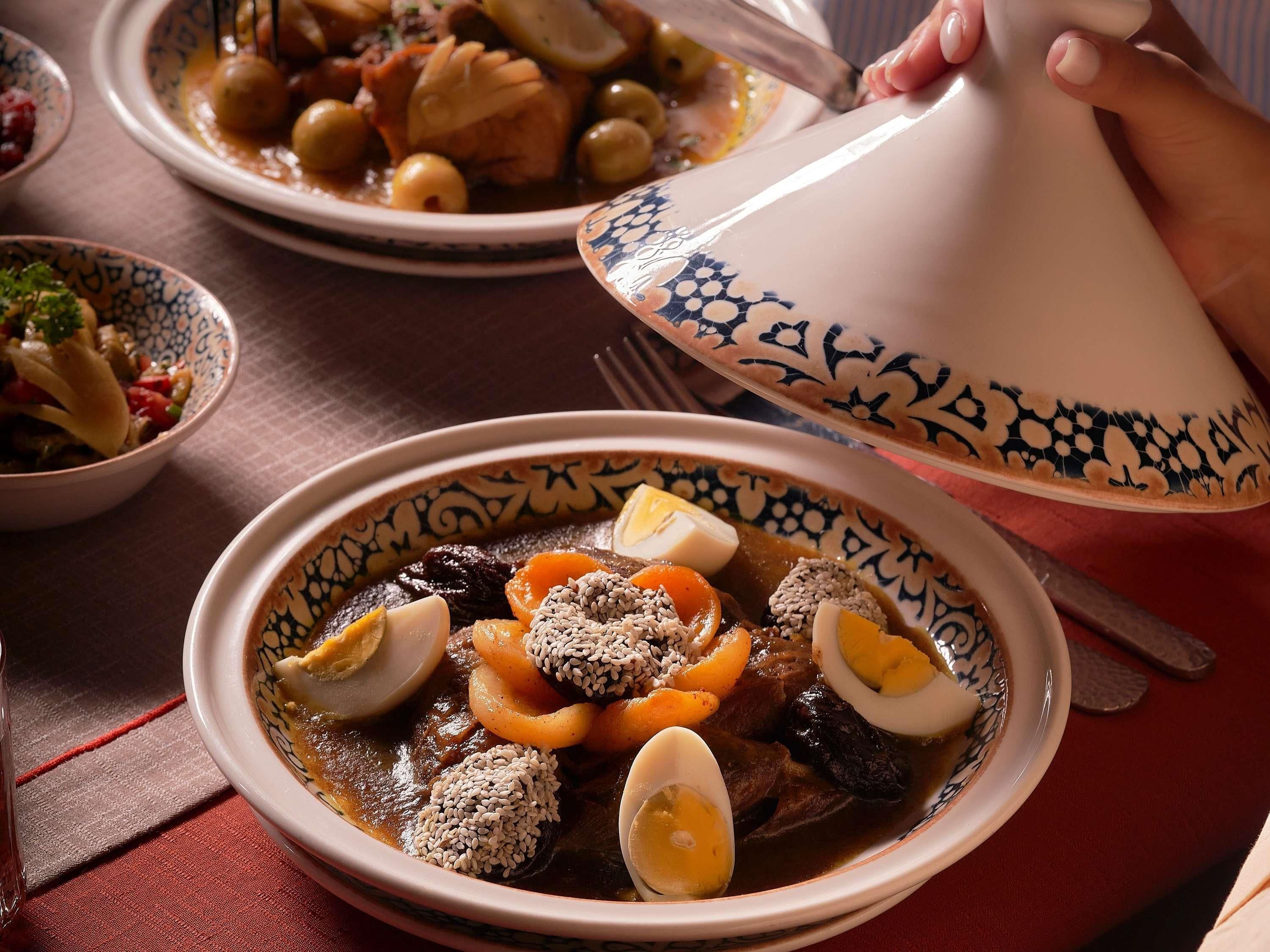 A traditional Moroccan tagine dish with eggs, vegetables, and meat, served in a patterned bowl.