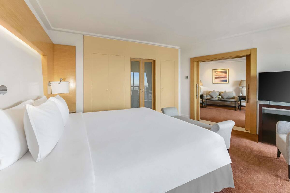 A hotel room with a large bed, a desk, a television, and a seating area with a sofa and chairs.