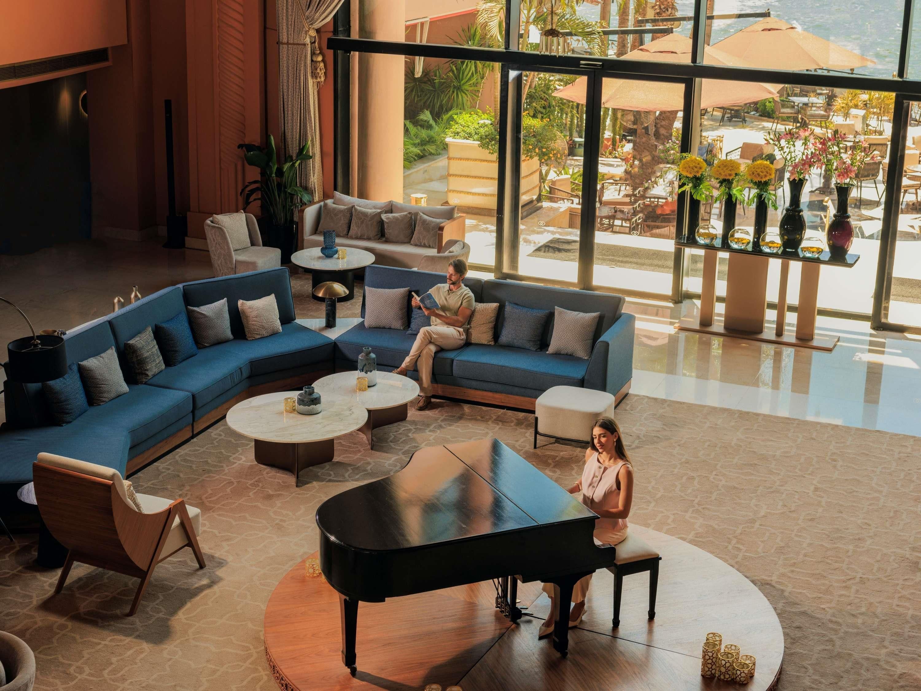 A spacious lobby with a grand piano, comfortable seating areas, and a view of the outdoor patio.