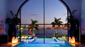A pool area with a view of a city skyline at dusk, lounge chairs, and candles.