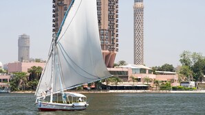 A sailboat on a body of water with a tall building in the background. - Sofitel Cairo Nile El Gezirah (Cairo)